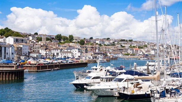 A marina with boats docked, surrounded by a town with buildings and hills in the background. - Tom Thumb - One Bedroom Cottage, Sleeps 2 (Mabe Burnthouse)