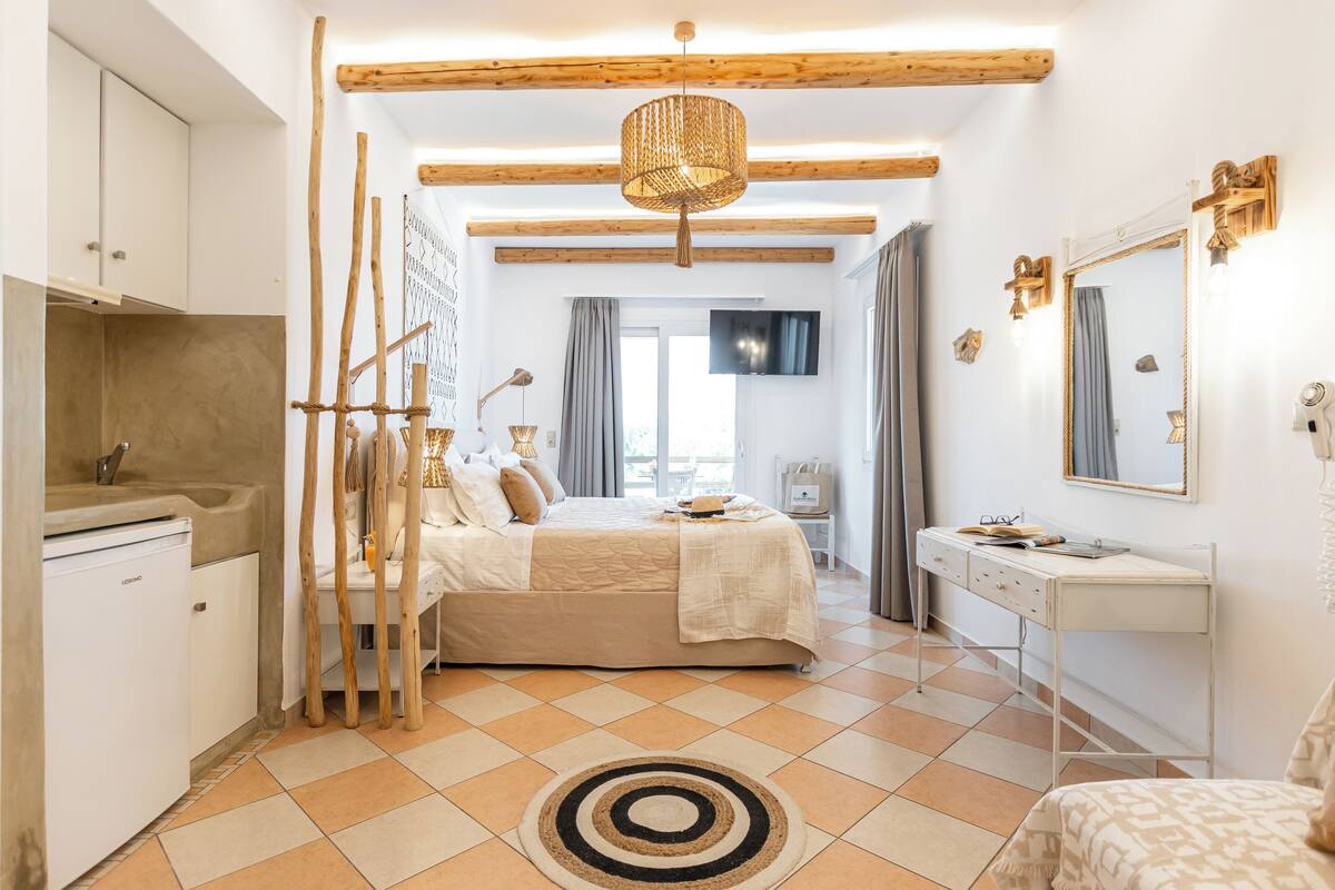 A bedroom with a bed, bedside table, dresser, and a large mirror.