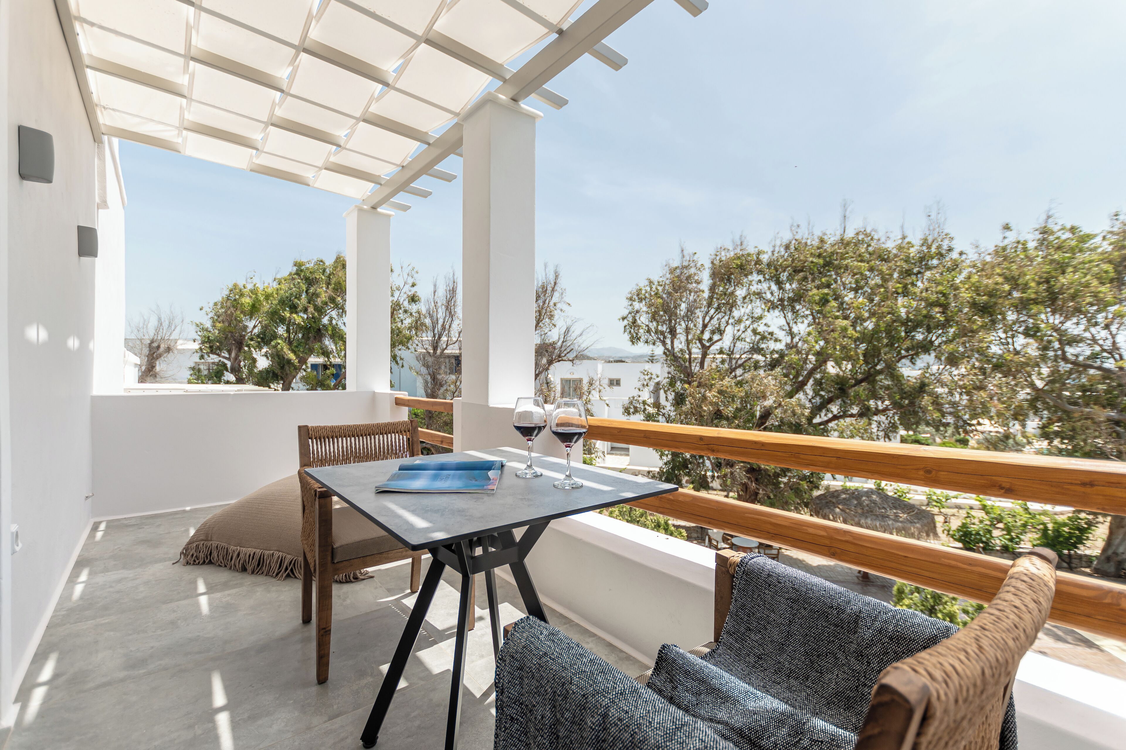 A balcony with a table, two chairs, and a view of trees and buildings.