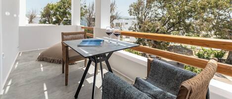 A balcony with a table, two chairs, and a view of trees and buildings.