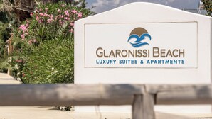 A sign for Glaronissi Beach Luxury Suites & Apartments with a logo of a wave and sun. - Glaronissi Beach (Naxos)