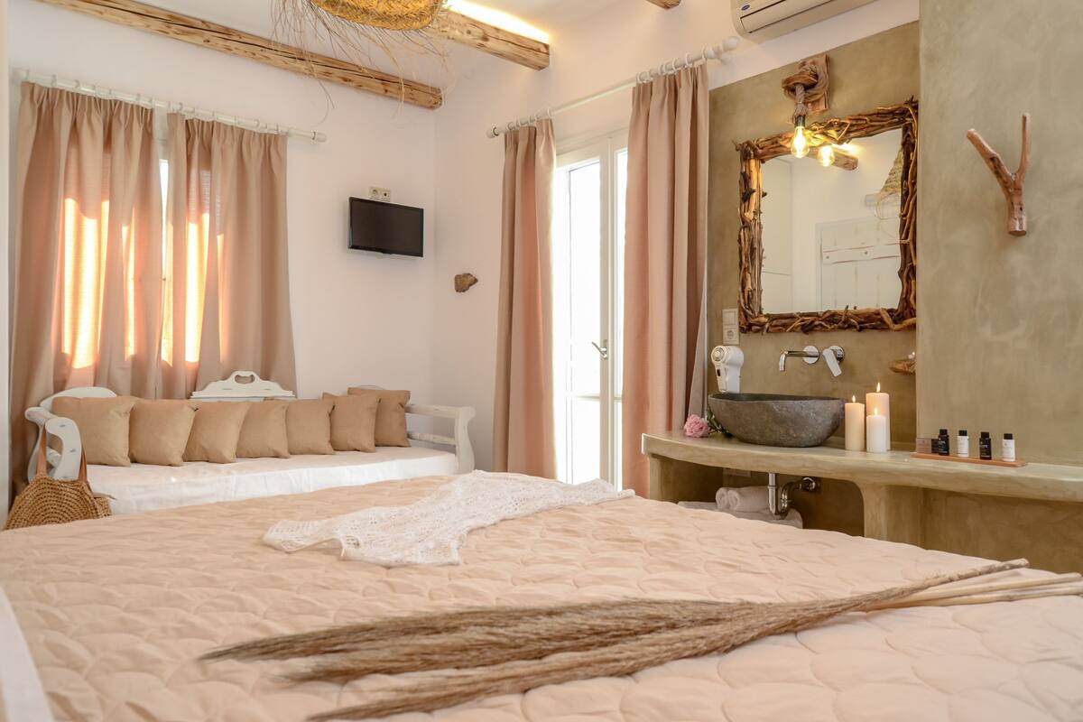 A bedroom with a bed, a bedside table, a vanity with a mirror, and a window with curtains.