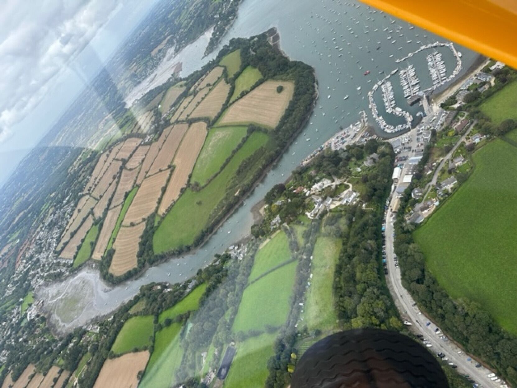 Vista aerea di un paesaggio con campi, un fiume e un piccolo borgo con strade e edifici.
