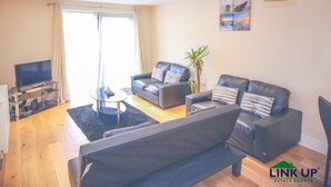 Een moderne woonkamer met een bank, een bijzettafeltje en een televisie.