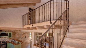 A spacious kitchen with a stone wall, a wooden island, and a staircase with a wrought iron railing. - Stunning Renovated Traditional Stone Villa, Private Pool & Mountain Views just 800 m from the Sea! (Stari Grad)