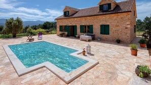 A stone house with a swimming pool, outdoor furniture, and potted plants. - Stunning Renovated Traditional Stone Villa, Private Pool & Mountain Views just 800 m from the Sea! (Stari Grad)