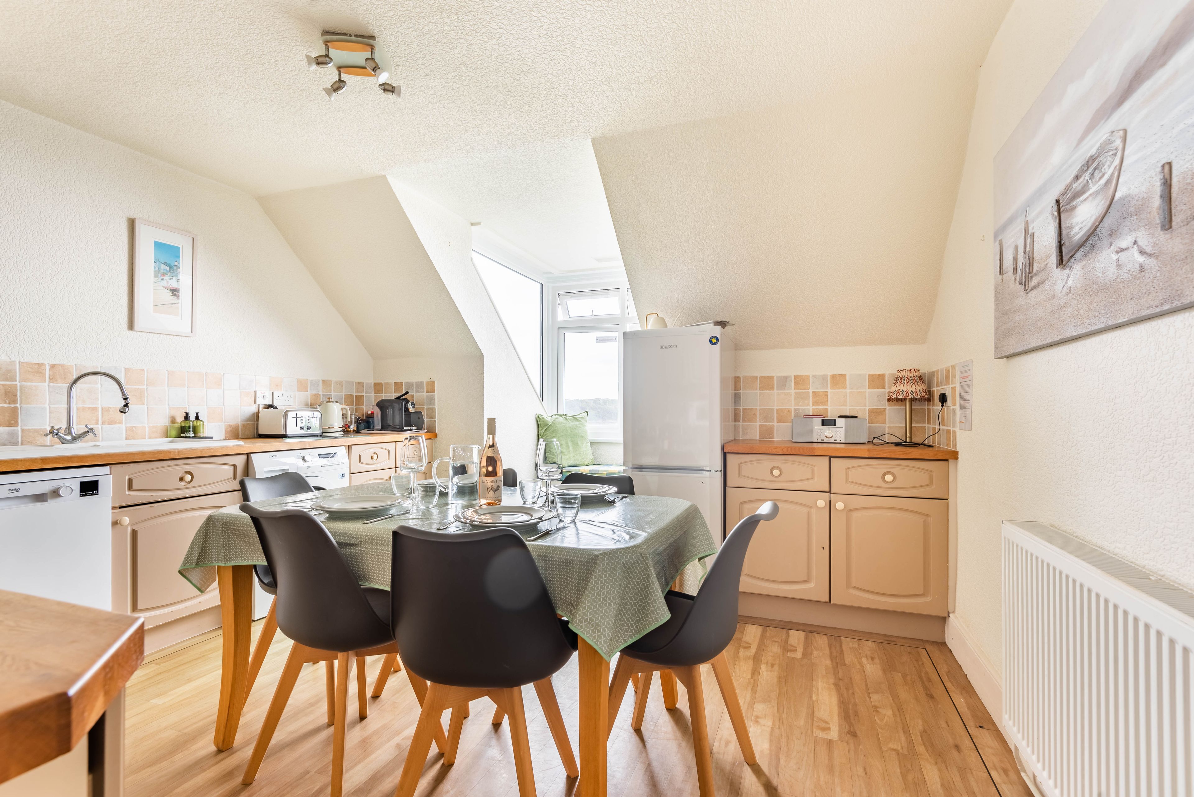 A kitchen with a dining table set for four, a refrigerator, and a window providing natural light.