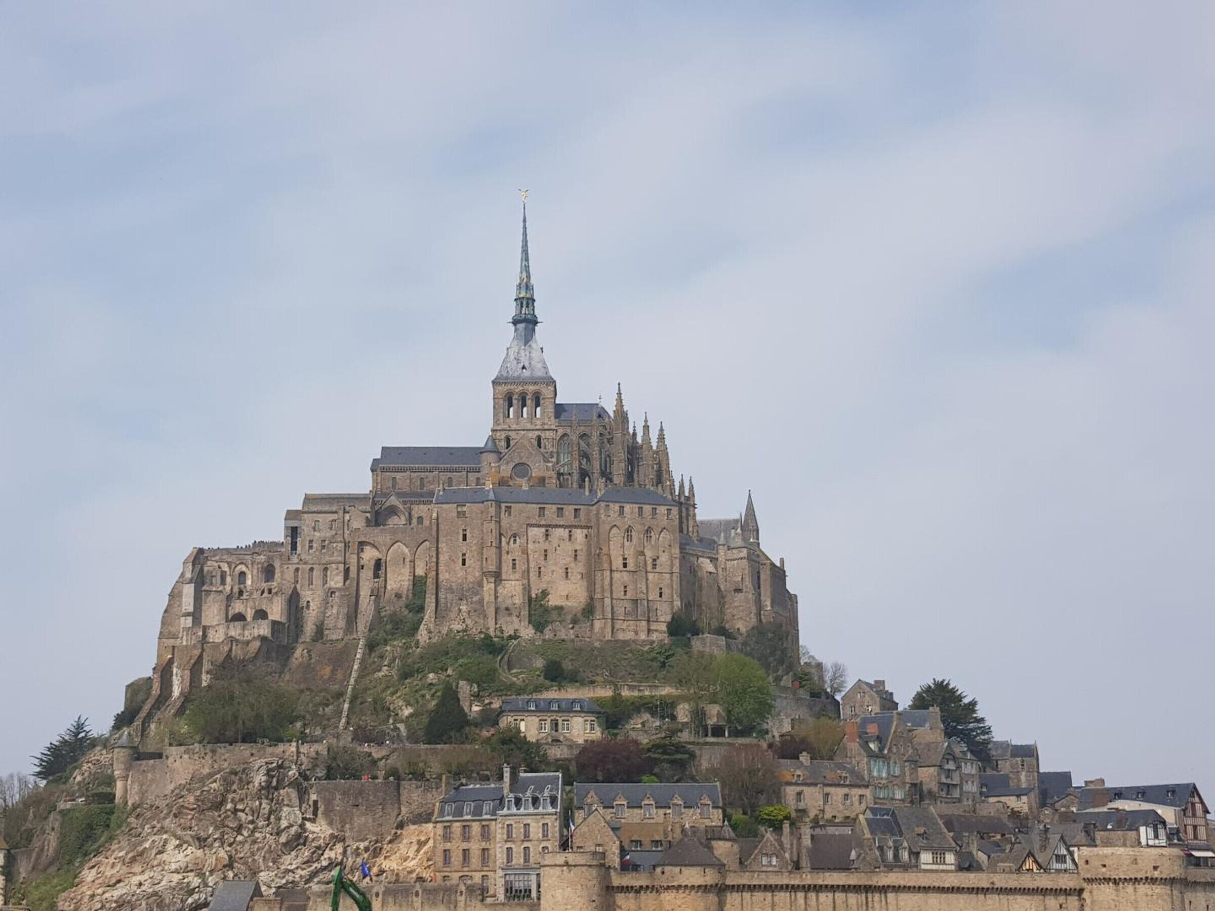 Eine historische Burg mit einem markanten Turm, gelegen auf einem Hügel mit Blick auf eine Stadt.