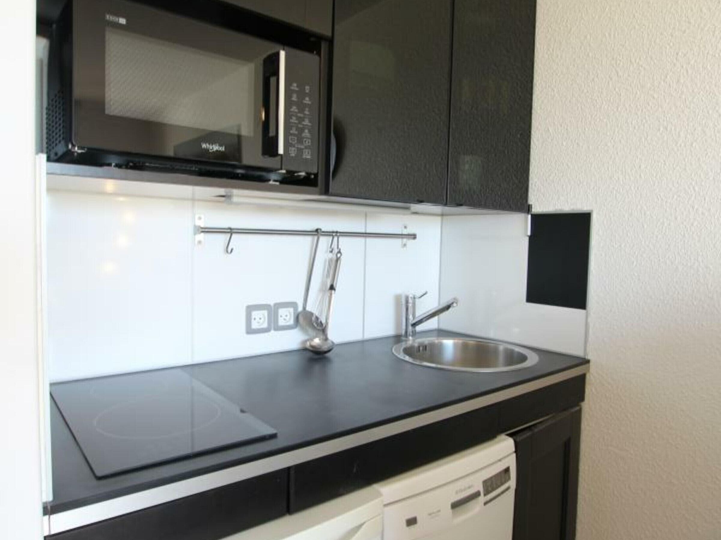 A compact kitchen with a microwave, a sink, and a dishwasher.