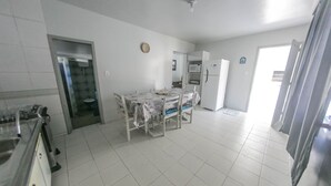 A spacious kitchen with a dining table, a refrigerator, and a microwave. - Casa 2 Amarela - Casa piscina 10 pessoas (Itapema)