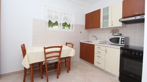 Een keuken met houten kastjes, een magnetron, een fornuis en een eettafel met stoelen.