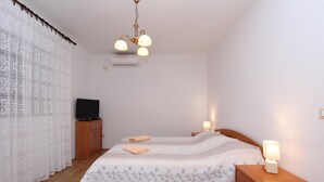 Een slaapkamer met een bed, een houten nachtkastje, een televisie en een plafondlamp.