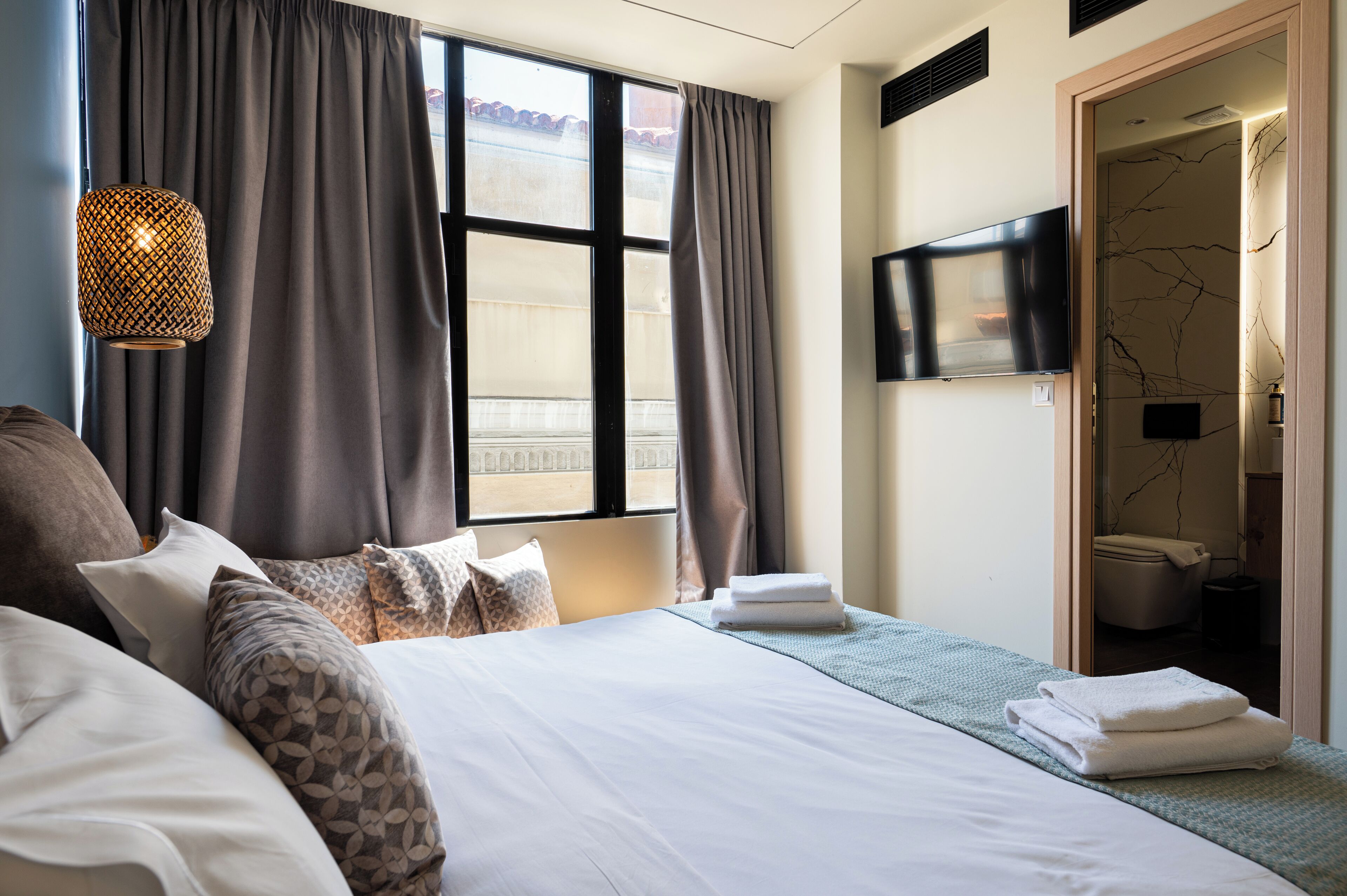 A hotel room with a large bed, a television mounted on the wall, and a bathroom visible through an open door.