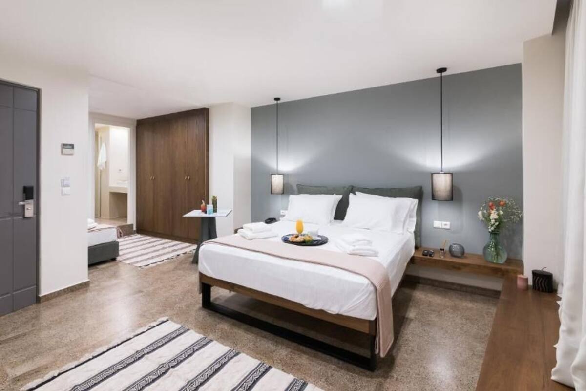 A modern bedroom with a large bed, bedside tables, a wardrobe, and a mirror.