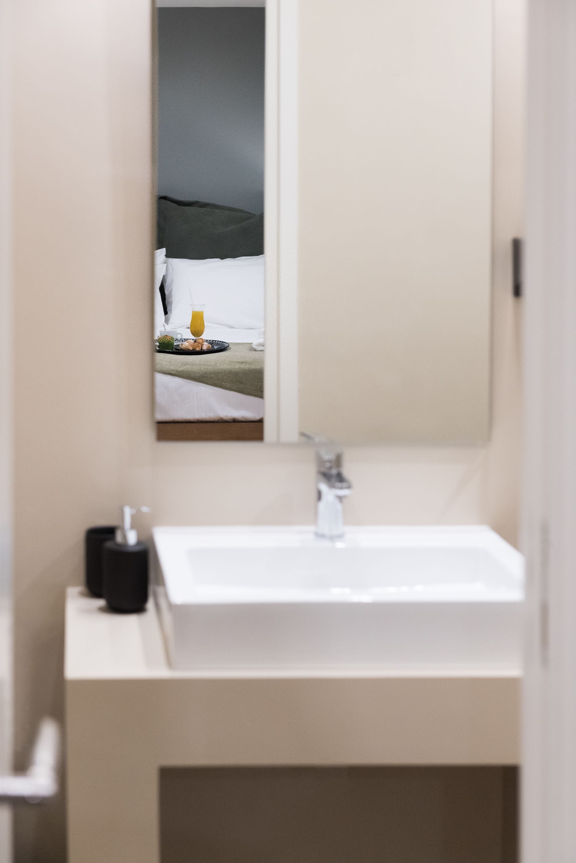 A bathroom with a white sink, a mirror, and a towel rack.