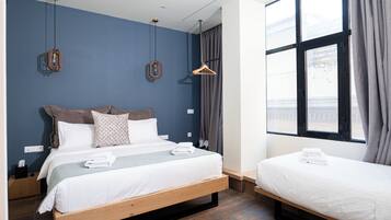 Una habitación de hotel con una cama grande, una cama más pequeña y una ventana con cortinas.