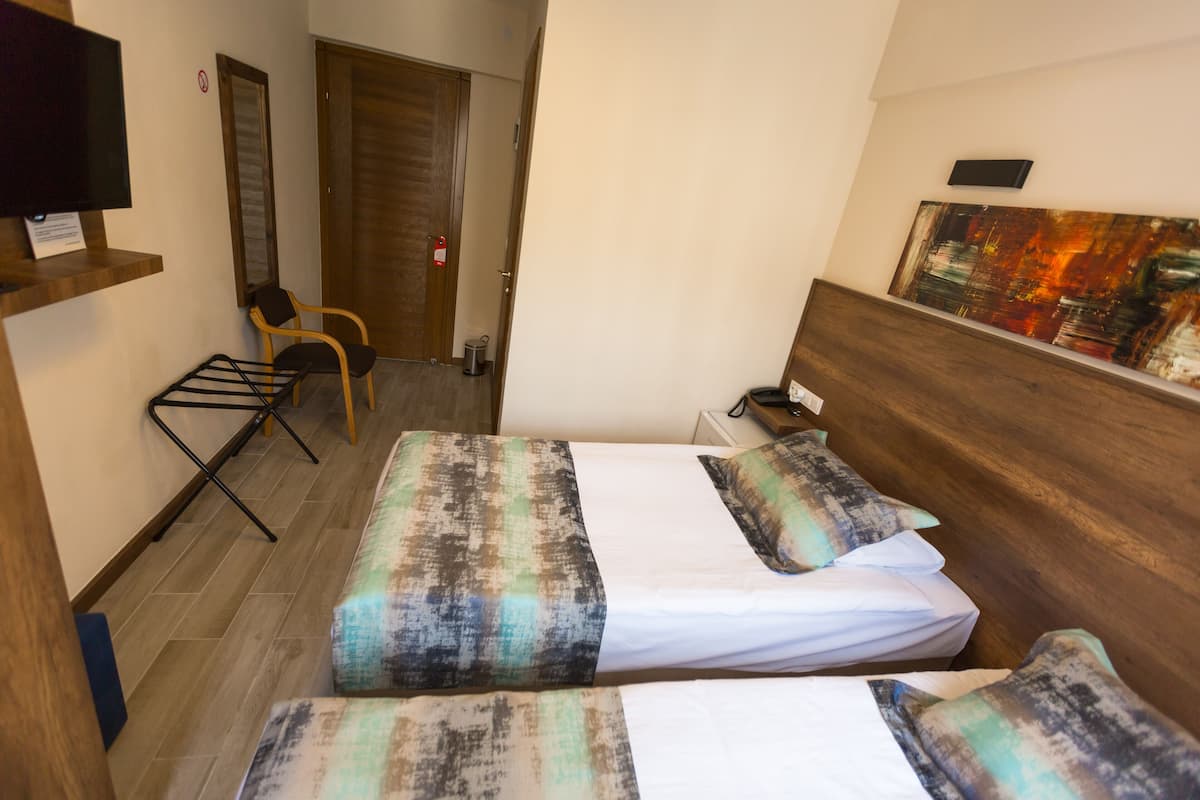 Une chambre d’hôtel avec un lit, une chaise, une télévision et un tableau au mur.