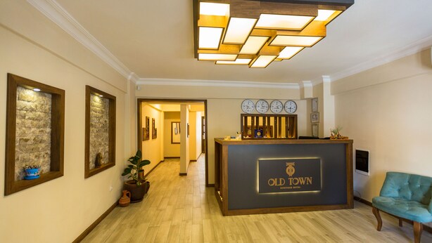 A reception area with a wooden reception desk labeled "Old Town Boutique Hotel," a clock, and a blue chair. - Old Town Boutique Hotel (Kusadasi)