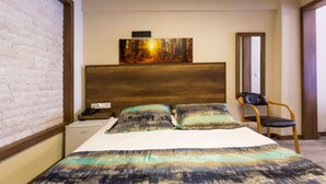 A bedroom with a large bed, a wooden headboard, a nightstand, a chair, and a painting on the wall. - Old Town Boutique Hotel (Kusadasi)