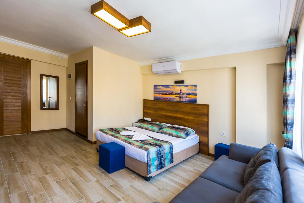 Une chambre d’hôtel avec un lit, un canapé, un tableau et un plancher en bois.