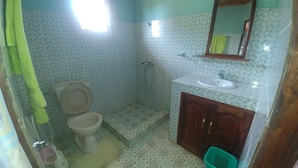 Ein Badezimmer mit Toilette, Dusche, Waschbecken und Spiegel.