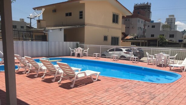 A swimming pool with white lounge chairs and a brick patio.