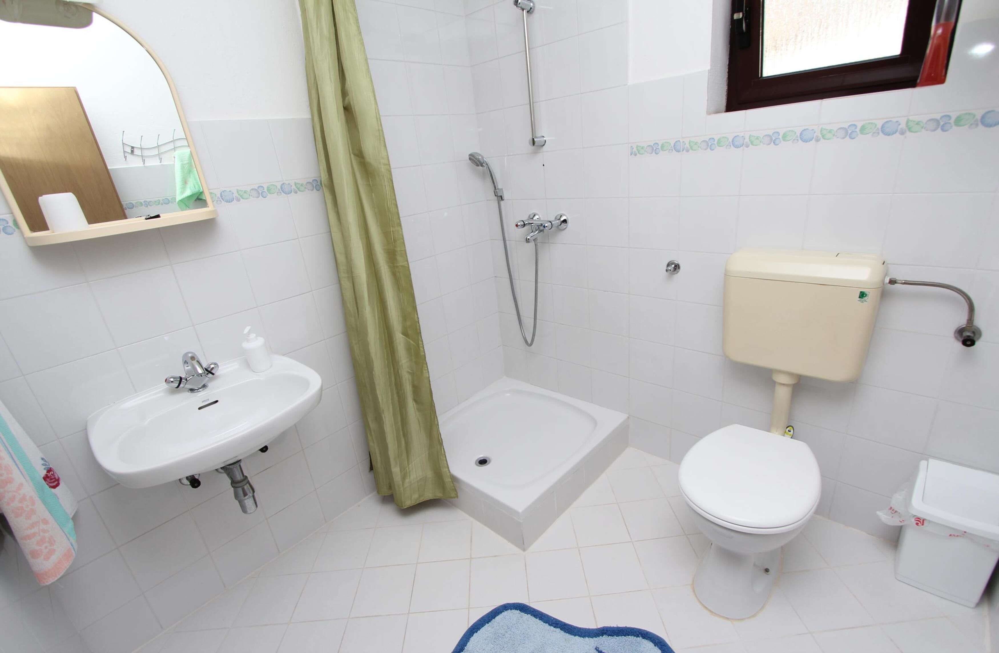 Une salle de bain équipée d’un lavabo, de toilettes, d’une douche et d’un miroir.