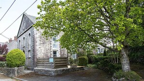 A stone building with a pitched roof, a small front porch, and a well-maintained lawn. - Providence House - Four Bedroom Cottage, Sleeps 8 (Saint Breward)