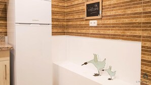 A kitchen with a white refrigerator, a chalkboard with 'Welcome' written on it, and a decorative bird sculpture on the countertop. - Mariblanca Bajo B Deluxe Living4malaga (Málaga)