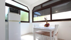A kitchen with a white refrigerator and a dining table with chairs. - Apartments Rozi (Rovinj)