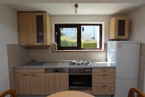 Kitchen features a gas stove, dishwasher, and refrigerator, with a window above the sink offering a view of the surrounding greenery.