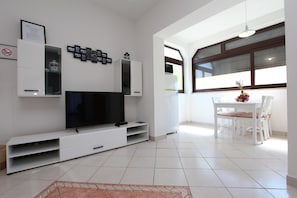 Relax in this stylish living room with a flat-screen TV, dining area, and ample storage.