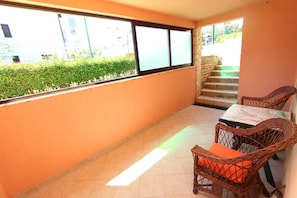 Enjoy the view from this balcony with a stone staircase, wicker chairs, and a small table.