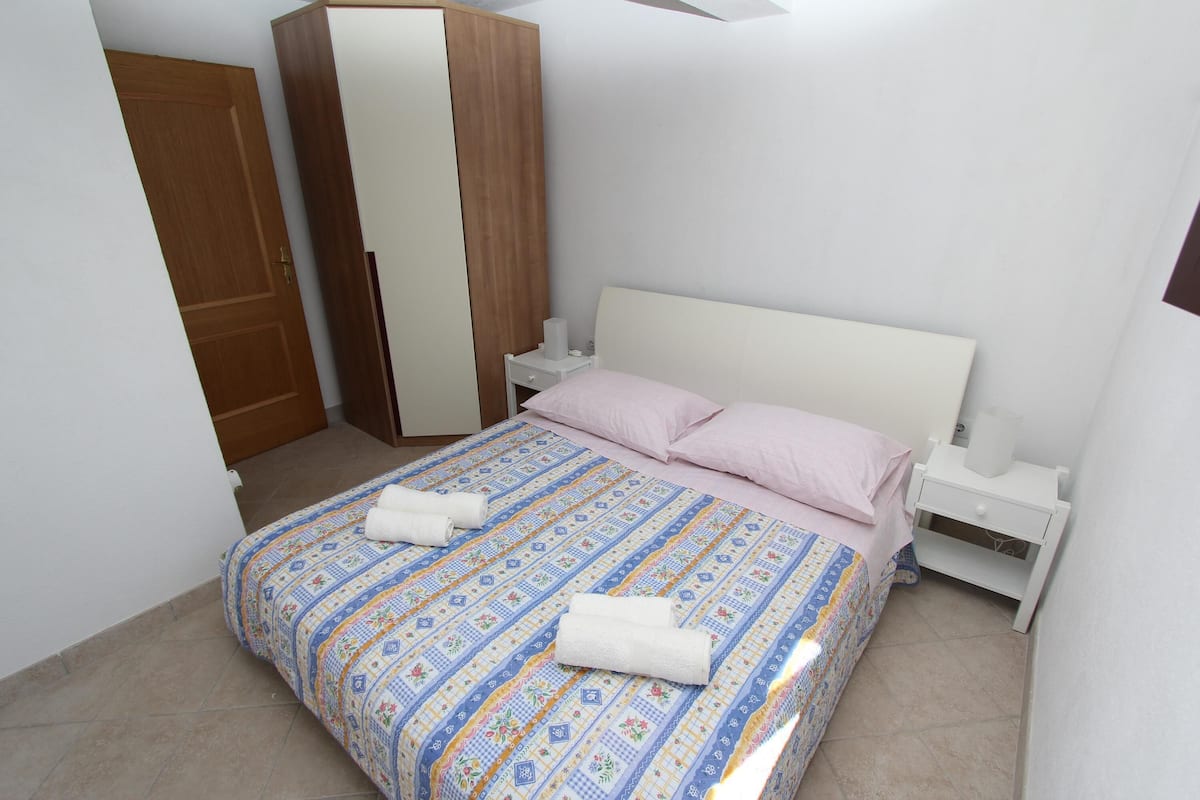 Une chambre à coucher comprenant un lit, deux tables de chevet, une armoire en bois et une porte.