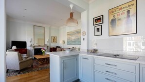 A modern kitchen with a central island, a dining area with a sofa and table, and a living room with a TV and fireplace.