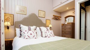A neatly arranged bedroom with a large bed, a dresser, and a mirror. - Sinclair Sophistication, by Veeve (London)