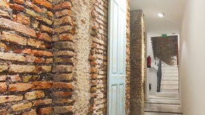 A corridor with a brick wall, a blue door, and a staircase leading to another floor. - Skyline 3 Living4malaga (Málaga)