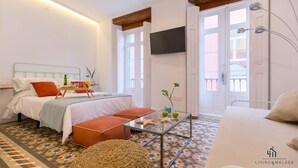 A modern hotel room with a bed, a glass coffee table, a sofa, and a TV mounted on the wall. - Skyline 3 Living4malaga (Málaga)