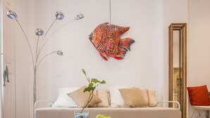A modern living room with a sofa, a glass coffee table, and a colorful fish wall art piece. - Skyline 3 Living4malaga (Málaga)