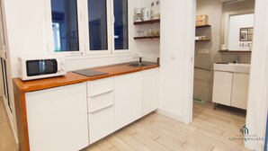 A compact kitchen with white cabinets, a wooden countertop, a microwave, and a window. - Skyline 3 Living4malaga (Málaga)