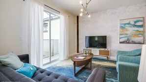 A modern living room with a sofa, armchair, coffee table, and a TV. - Champions Gate Exec Villas- 8983sd (Davenport)