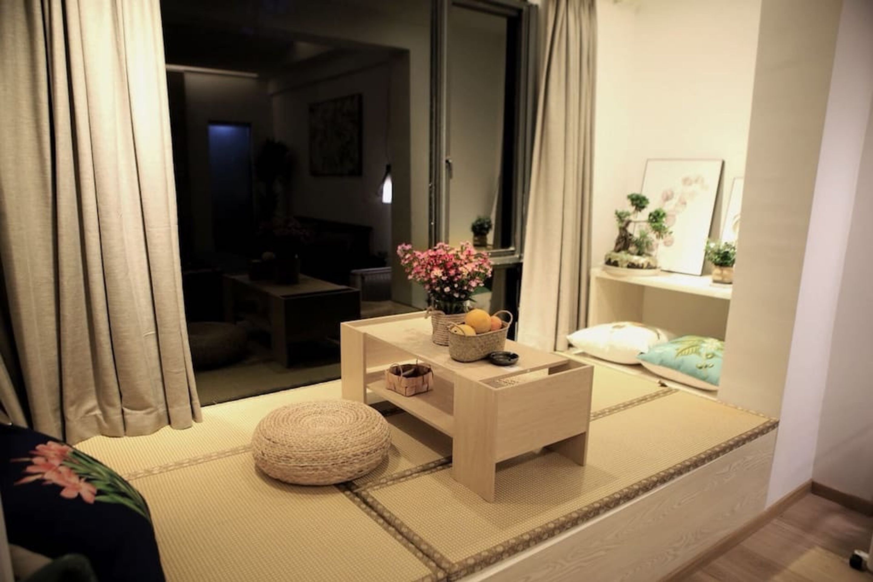 Un salón acogedor con suelo de tatami, una mesita de centro de madera y un pequeño cojín redondo.