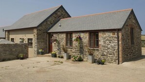 A stone building with a sloped roof, a front entrance, and potted plants. - Skylark - Three Bedroom Cottage, Sleeps 6 (Camborne)