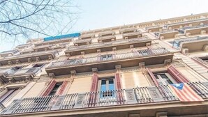 Een meerlaags gebouw met versierde balkons en een vlag op een van de balkons.