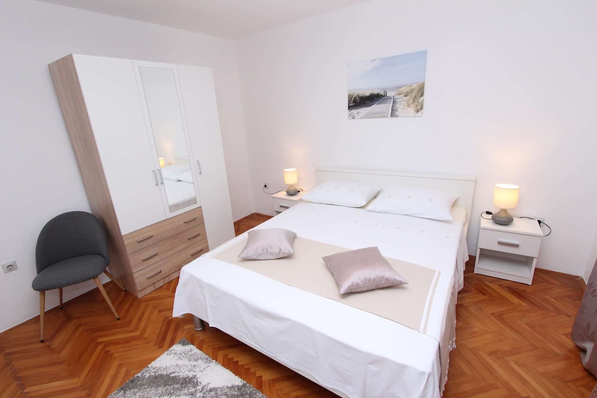A bedroom with a bed, bedside tables, a wardrobe, and a chair.
