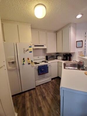 Kitchen with a refrigerator, stove, microwave, and sink, offering a clean and functional space.