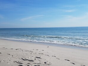 A beach with footprints in the sand and a clear view of the ocean.