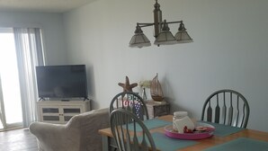 Un coin repas avec une table en bois, des chaises, un téléviseur et un lustre.