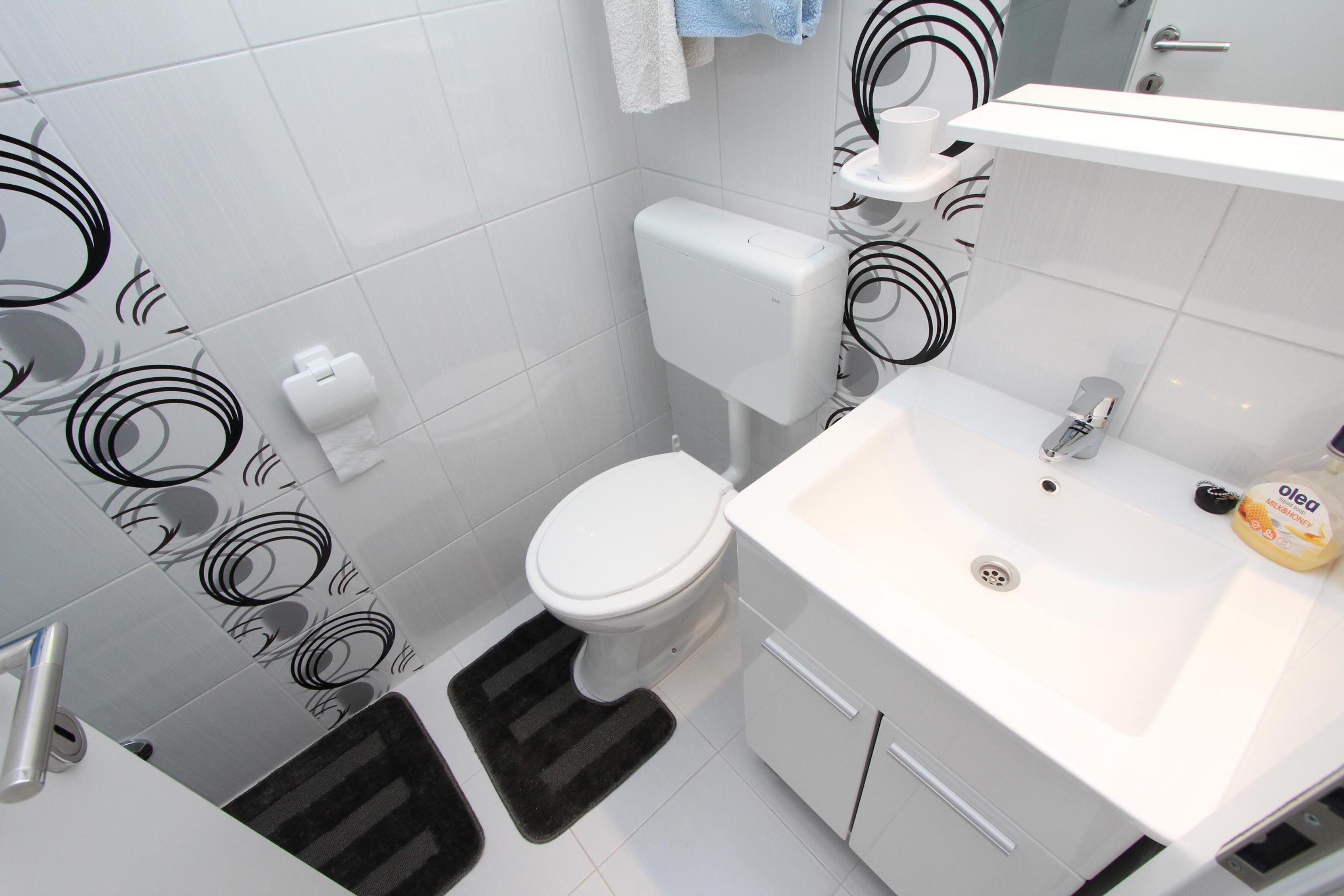 Une salle de bain moderne équipée de toilettes, d’un lavabo et d’un porte-serviettes.