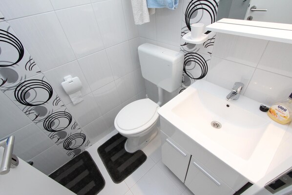 A modern bathroom with a toilet, sink, and a towel rack. - Apartments Santin (Rovinj)